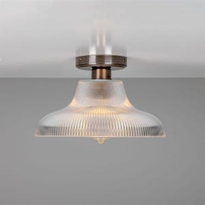 May include: A ceiling light fixture with a clear glass shade with vertical lines. The fixture has a bronze finish.