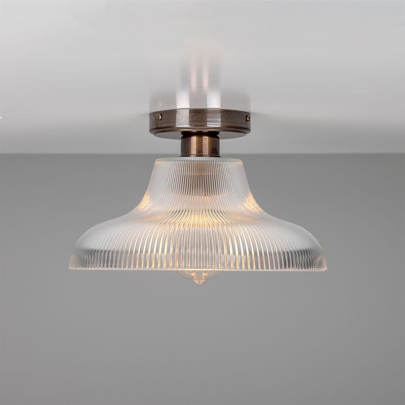 May include: A ceiling light fixture with a clear glass shade with vertical lines. The fixture has a bronze finish.