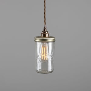 Könnte beinhalten: Eine transparente Glas-Pendelleuchte mit einer Edison-Glühbirne im Vintage-Stil. Das Licht wird von einem braunen Kabel gehalten und hat eine Metallkappe und einen gläsernen Lampenschirm in Form eines Einmachglases. Auf dem Glasschirm ist der Text "Le Parfait" eingeprägt.