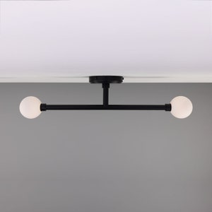 May include: A black ceiling light fixture with two white frosted glass globes. The fixture has a straight bar connecting the globes.