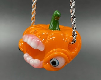 Colgante de calabaza de cristal naranja chillón con ojo que brilla en la oscuridad
