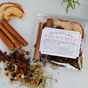 Puede incluir: Una bolsa transparente llena de una mezcla para cocinar a fuego lento con la etiqueta "Witch's Brew". La bolsa contiene rodajas de manzana deshidratadas, palitos de canela, anís estrellado y otras especias. El texto de la etiqueta dice "Halloween Vibes & Spooky Season Magic".