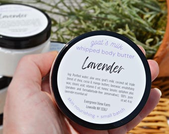 Könnte beinhalten: Weiße, aufgeschlagene Ziegenmilch-Körperbutter in einem runden Behälter mit schwarzem Deckel. Das Etikett trägt die Aufschrift Lavender, Evergreen View Farm, Lowville NY 13367, und listet Inhaltsstoffe wie Aloe Vera, Shea-, Kakao- und Mangobutter.
