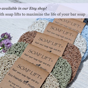 May include: A close-up of six soap lifts made of natural materials. The soap lifts are in various colors, including beige, brown, green, and blue. The soap lifts are arranged in a row, with the text "SOAP LIFT" and "Rest your soap high and dry" printed on each one. The text "Eco Friendly bio Plastic" is printed on the bottom soap lift.