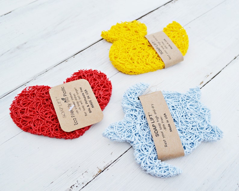 May include: Three colorful soap savers in the shapes of a heart, a duck, and a turtle. The soap savers are made of a woven material and are designed to help extend the life of soap bars. The packaging includes the text "SOAP LIFT" and "Eco Friendly Bio Plastic".