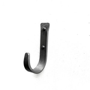 May include: A black metal hook with a J-shape, mounted on a white wall.