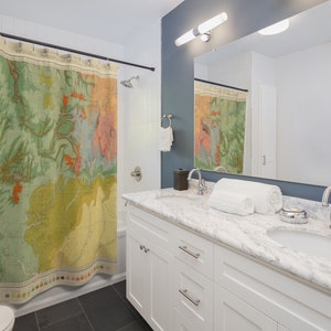 May include: A white bathroom vanity with a marble countertop and two sinks. The vanity has two drawers and two doors. A shower curtain with a vintage map design is visible in the background.