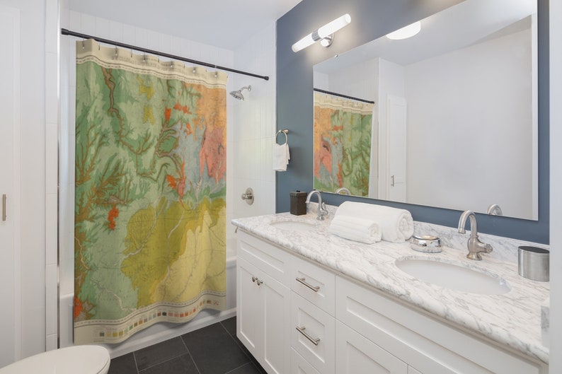 May include: A white bathroom vanity with a marble countertop and two sinks. The vanity has two drawers and two doors. A shower curtain with a vintage map design is visible in the background.