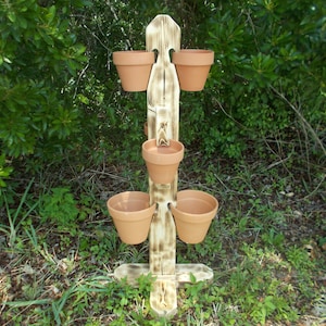 May include: A wooden plant stand with five terracotta pots. The stand is weathered and has a rustic look. The pots are empty and ready to be planted.