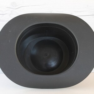 May include: A black felt hat with a wide brim and a deep crown. The hat is made of a soft, pliable material and has a smooth, polished finish.