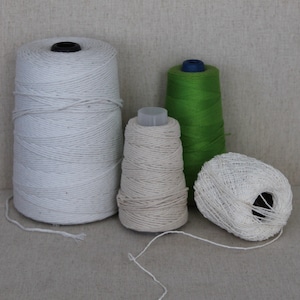 May include: Four spools of white cotton thread, one green spool of thread, and one white spool of thread in a net-like pattern.