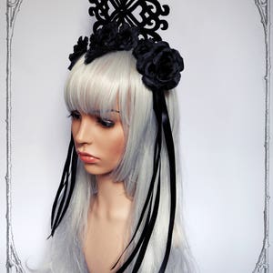Puede incluir: Diadema de encaje negro con un dise&ntilde;o grande e intrincado y rosas de tela negra. La diadema tiene largas cintas negras.