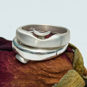 May include: Two silver rings stacked on top of each other, resting on a dried rose bud.