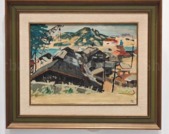May include: An oil painting depicting a coastal town with dark rooftops, set against a backdrop of a mountain range and a blue sky. The artwork is framed in a green and brown wooden frame.