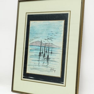 May include: A framed watercolor painting of a seascape with a row of boats in the water. The sky is blue with white clouds and there are birds flying overhead. The painting is signed "G. Lang" in the bottom right corner.