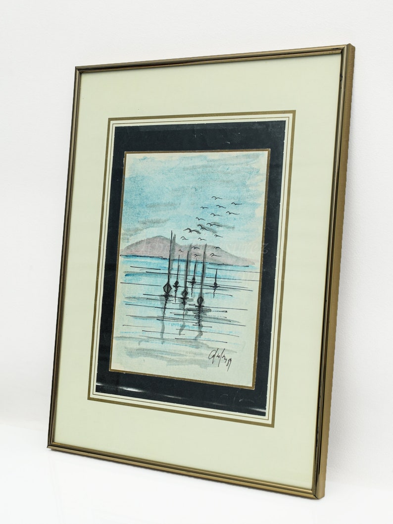May include: A framed watercolor painting of a seascape with a row of boats in the water. The sky is blue with white clouds and there are birds flying overhead. The painting is signed "G. Lang" in the bottom right corner.