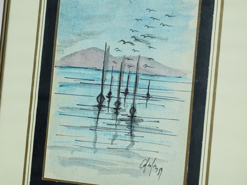 May include: A watercolor painting of a seascape with a distant island and a flock of birds flying overhead.  There are several sailboats anchored in the water with their reflections visible. The painting is signed "G.Wilson 79".
