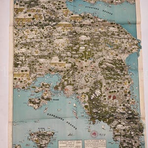 Może przedstawiać: Zabytkowa ilustrowana mapa regionu Attyki w Grecji, zawierająca szczegółowe rysunki topograficzne terenu, obszarów przybrzeżnych i wysp. Mapa zawiera tekst w języku greckim, niebieskie zbiorniki wodne oraz zielone obszary lądowe z punktami orientacyjnymi.
