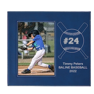 May include: A blue leather photo frame with a stitched border. The frame has a baseball-themed design with crossed bats and a baseball with the number 24. The text "Timmy Peters BALINE BASEBALL 2022" is engraved below the baseball. The frame includes a photo of a young baseball player in a batting stance.
