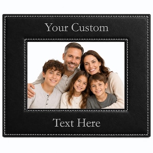May include: A rectangular black leather photo frame with white contrast stitching along the inner and outer edges. The frame features the engraved text Your Custom at the top and Text Here at the bottom, surrounding a photograph of a family.