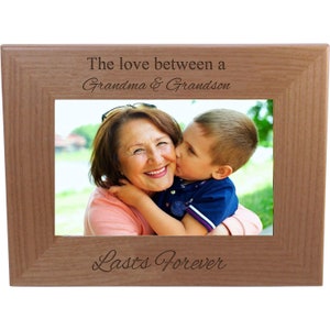 May include: A wooden picture frame with a photo of a grandmother and grandson. The frame is engraved with the text "The love between a Grandma & Grandson Lasts Forever".
