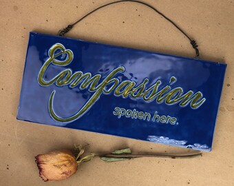 Compassion Spoken Here.  Fired Ceramic Wall Sign.  One-Of-A-Kind In Blue With Green Letters.