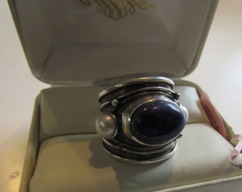 May include: A silver ring with a large blue lapis lazuli stone and two white pearl accents. The ring is in a white box.