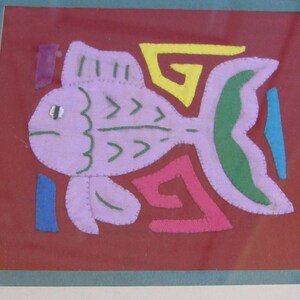 May include: A framed artwork featuring a purple fish with green and yellow details, surrounded by colorful geometric shapes on a red background.