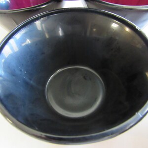 May include: A black ceramic coffee mug with a smooth, glossy finish. The mug is empty and the inside is visible.