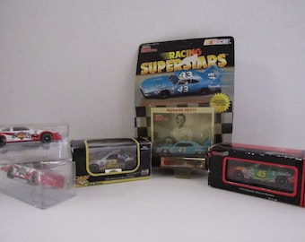 May include: Five unopened boxes of NASCAR die-cast cars. The boxes are all different colours and feature different drivers. The cars are all in 1/24 scale. The boxes are all in good condition.