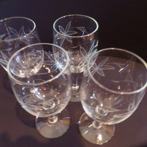 May include: Set of four clear glass wine glasses with an etched leaf design.