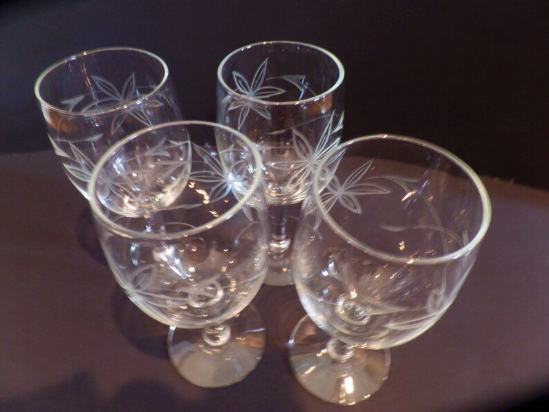 May include: Set of four clear glass wine glasses with an etched leaf design.