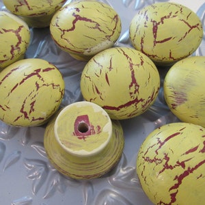 May include: A set of nine yellow and red distressed wooden knobs. The knobs have a crackled finish and are perfect for adding a vintage touch to furniture.