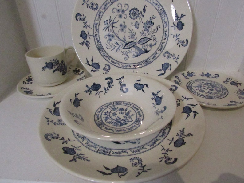 May include: A set of blue and white china dinnerware with a floral pattern. The set includes a dinner plate, side plate, bowl, and teacup and saucer.