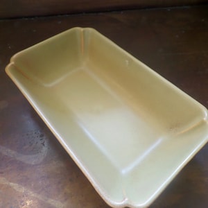 以下が含まれることがあります： 長方形で、わずかに丸みを帯びた縁を持つ、薄いベージュ色のセラミック製のパン型です。