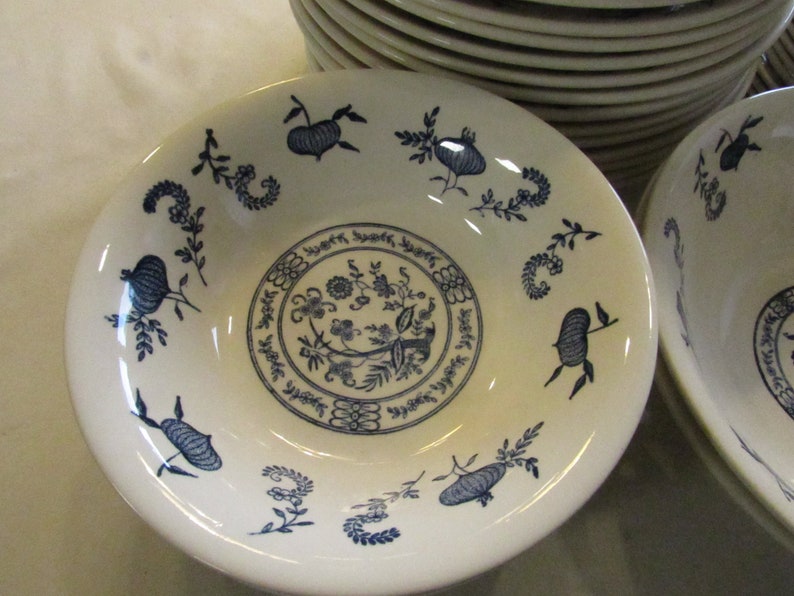 May include: A white ceramic bowl with a blue floral design. The bowl has a wide rim and a deep well. The floral design is intricate and features a variety of flowers and leaves.
