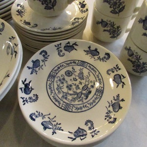 May include: A set of white ceramic dishes with a blue floral pattern. The dishes include bowls, plates, and saucers.