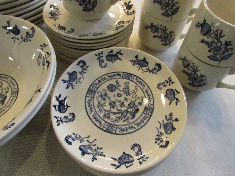 May include: A set of white ceramic dishes with a blue floral pattern. The dishes include bowls, plates, and saucers.
