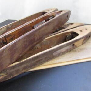 May include: Four wooden bobbins for weaving, stacked on top of each other. The bobbins are brown and have a natural wood finish. They are slightly worn and have a rustic look.