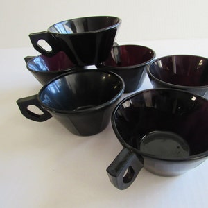 May include: Set of six black and purple glass cups with handles. The cups are stacked on top of each other.