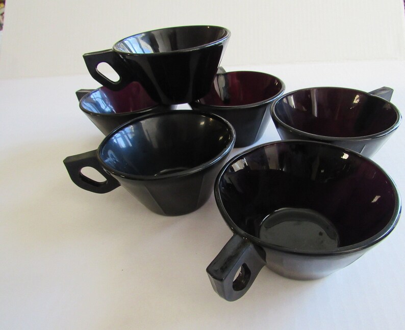 May include: Set of six black and purple glass cups with handles. The cups are stacked on top of each other.