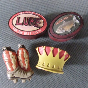 Könnte beinhalten: Vier dekorative Keramikornamente: ein rotes und weißes Oval mit dem Text "Fishing Co. Lure For The Best Catch", ein rotes und braunes Oval mit dem Text "Angling Co." und einem Fisch, ein Paar rot-weiße Cowboystiefel und eine gelbe Krone mit roter Spitze.