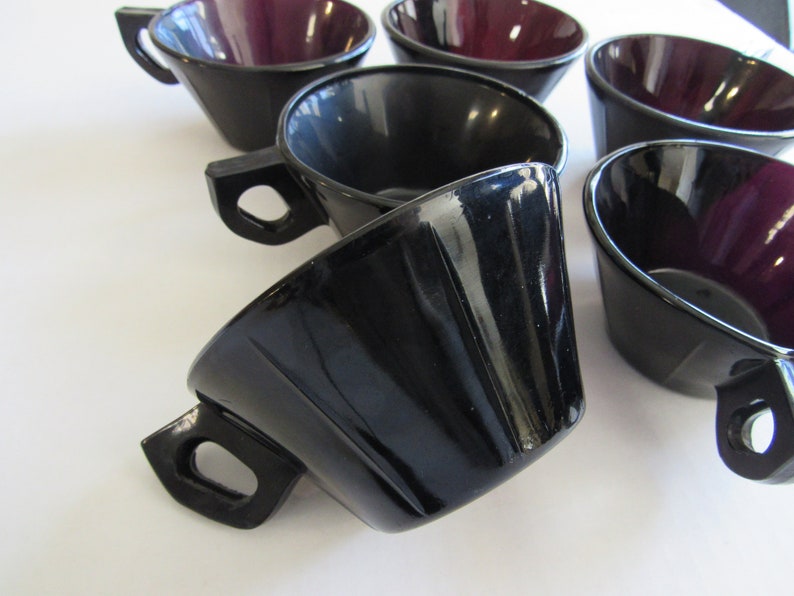May include: Set of six black and purple glass cups with a flared design. The cups have a glossy finish and are perfect for serving coffee, tea, or other beverages.