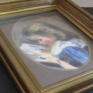 May include: A framed painting of a young girl with blonde hair, wearing a blue dress, reading a book. The painting is set in a gold frame.