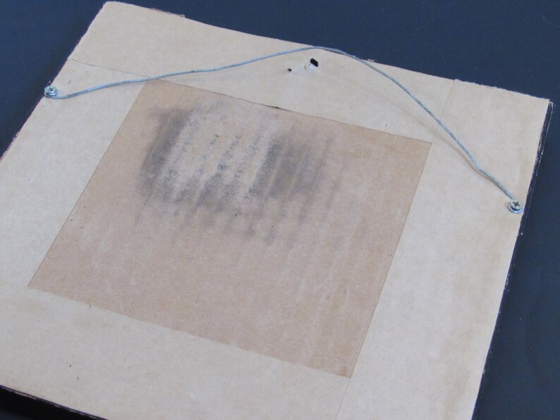May include: The back of a framed picture with a brown cardboard backing and a wire hanger attached with metal eyelets.
