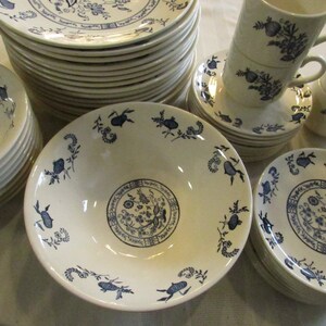 May include: A set of white ceramic dishes with a blue floral pattern. The set includes bowls, plates, and cups.