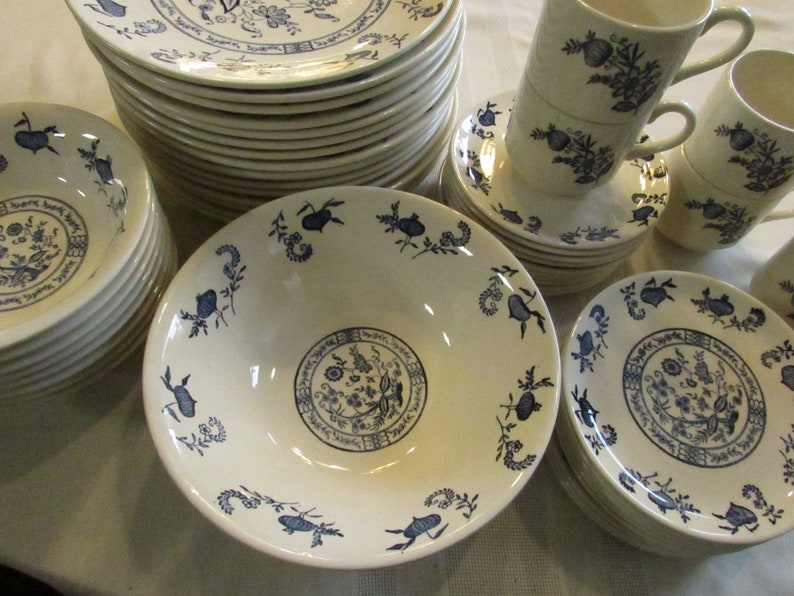 May include: A set of white ceramic dishes with a blue floral pattern. The set includes bowls, plates, and cups.