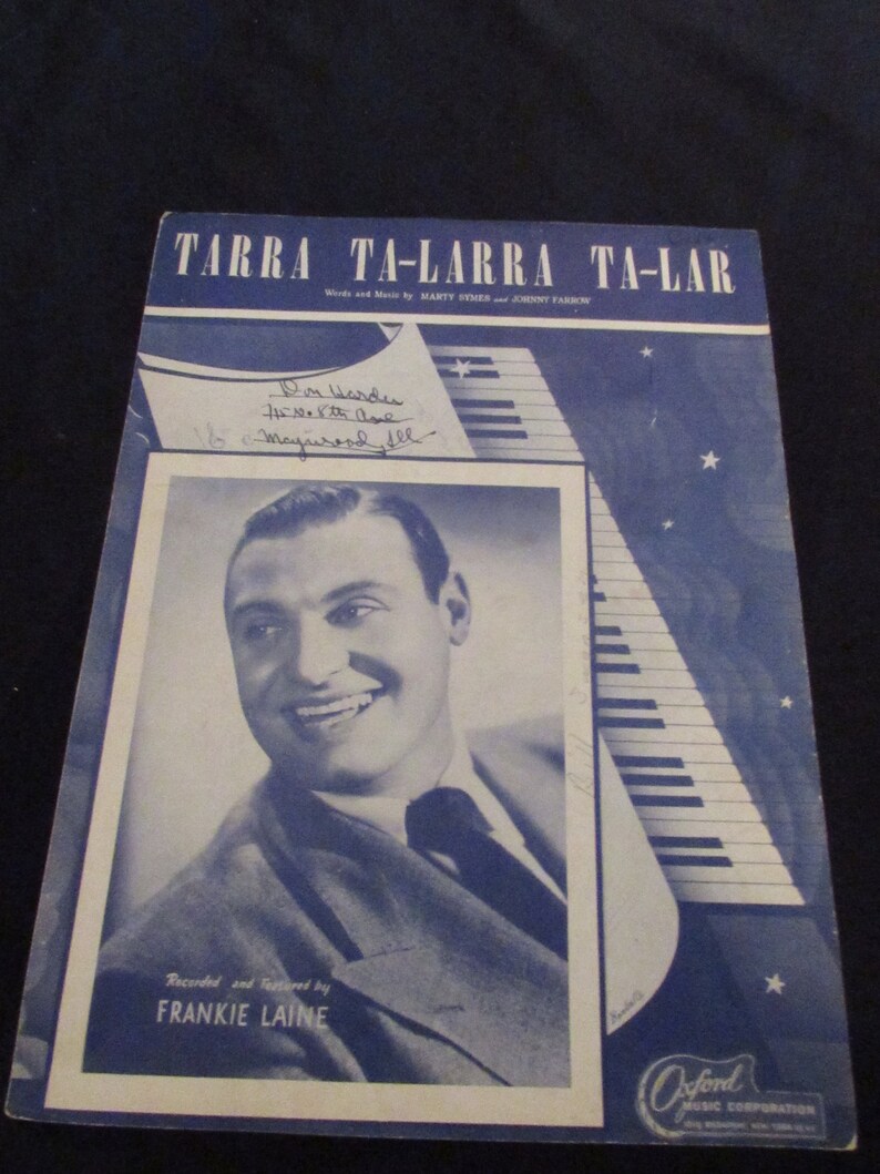 May include: A vintage sheet music cover for the song "Tarra Ta-Larra Ta-Lar" by Marty Symes and Johnny Farrow. The cover features a black and white photo of Frankie Laine, a popular singer from the 1940s and 1950s, with a signature in the top left corner. The cover is blue with white stars and a stylized piano.
