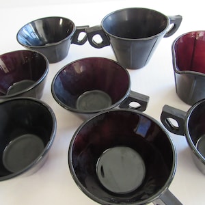 May include: Set of eight black and burgundy glass cups with handles. The cups are all the same size and shape, and they have a smooth, glossy finish.