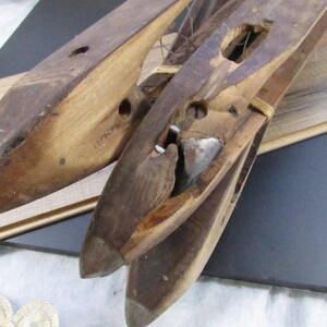 May include: Three wooden shoe lasts with metal tips. The lasts are stacked on top of each other. The top last has a metal piece attached to it. The lasts are made of wood and have a brown colour.